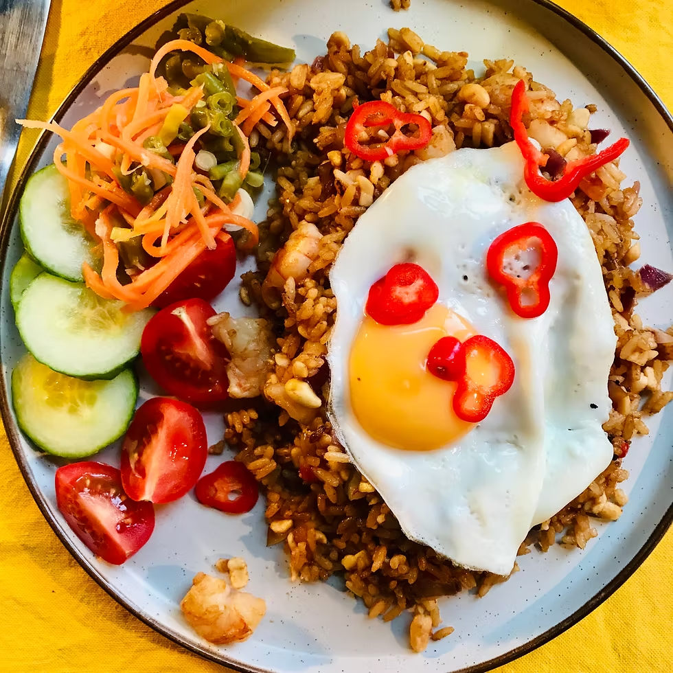 A plate of Nasi Goreng with a sunny-side-up egg and prawn crackers.